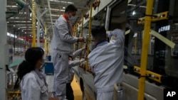 在中国湖北省十堰市的一家工厂，工人为一辆小客车安装窗板。(资料照片：2023年5 月10日)