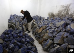 FILE - An Afghan businessman checks lapis lazuli at his shop in Kabul, March 28, 2016. The brilliant blue stone, prized for millennia, is found almost exclusively in Afghanistan and is a key part of the nation's mineral wealth.