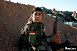 An Iranian-Kurdish female fighter holds her weapon during a battle with Islamic State militants in Bashiqa, near Mosul, Iraq, Nov. 3, 2016.