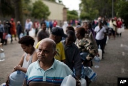 FILE - Residents queue to fill containers with water from a source of natural spring water in Cape Town, South Africa, Feb. 2, 2018.