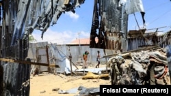 Des civils marchent près de la scène où un tir de mortier a détruit des maisons à l'extérieur d'un complexe tentaculaire qui abrite la base de la Mission de l'Union africaine en Somalie (AMISOM) à l'aéroport de Mogadiscio, en Somalie, le 25 mars 2021.