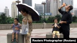 Parents with their children enjoy a drink in Shanghai August 30, 2002.