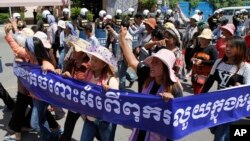 Cambodian activists shout slogans during a march toward the National Assembly, in Phnom Penh, Cambodia, Thursday, May 29, 2014. Some 300 activists on Thursday delivered petitions to the National Assembly and Anti-Corruption Unit headquarters to demand the government to stop giving land concession to private companies. The banner reads " Absolutely against the corruption in the society." (AP Photo/Heng Sinith)