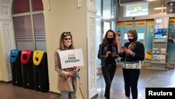 A supporter of Belarusian opposition blogger and activist Raman Pratasevich holding a placard reading 'I am/we are Raman Pratasevich waits for the arrival of a Ryanair flight after it was diverted to Belarus, at Vilnius Airport in Vilnius, May 23, 2021.