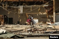 13-year-old Kaleb Cassel removes belongings from a flea market damaged by Hurricane Michael in Panama City, Florida, Oct. 11, 2018.