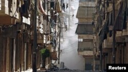 Asap mengepul di antara gedung-gedung di distrik Salah-Edinne, Aleppo, sesaat setelah digempur pasukan pemerintah Suriah (31/7).