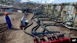 FILE - A worker helps monitor water pumping pressure and temperature at an oil and natural gas extraction site in Colorado, March 29, 2013.