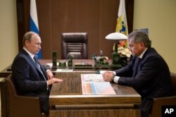 Russian President Vladimir Putin, left, listens to Defense Minister Sergei Shoigu during their meeting in the Bocharov Ruchei residence in the Black Sea resort of Sochi, Russia, Oct. 7, 2015.
