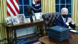 Biden family photos are displayed around a bust of activist Cesar Chavez, as U.S. President Joe Biden prepares to sign executive orders at the Resolute Desk inside the Oval Office of the White House in Washington, U.S., January 20, 2021. Picture taken Jan