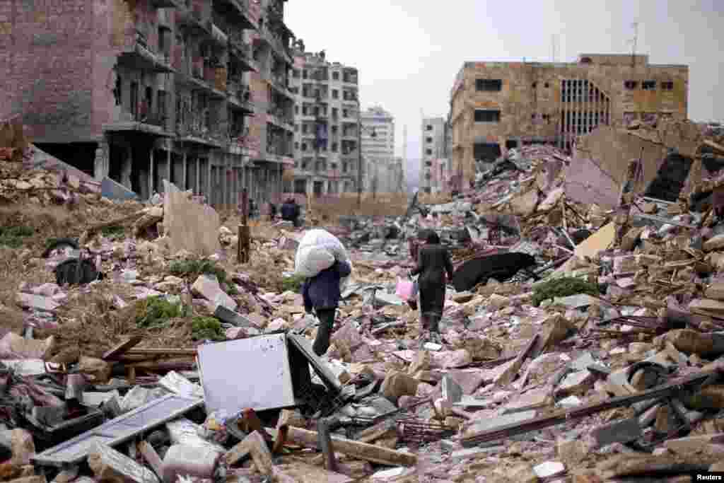  People walk amid the rubble as they carry belongings that they collected from their houses in the government controlled area of Aleppo, Syria, Dec. 17, 2016.