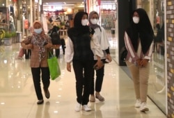 Perempuan mengenakan masker sebagai pencegahan penyebaran virus corona berjalan di sebuah pusat perbelanjaan di Tangerang, Senin, 1 Maret 2021. (Foto: AP/Tatan Syuflana)