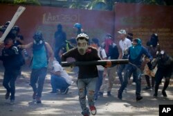 Anti-government protesters, one carrying a homemade mortar, take cover as security forces fire tear gas to disperse demonstrators in Caracas, Venezuela, May 1, 2019.