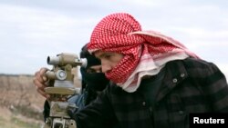 FILE - A Jaish al-Islam (Army of Islam) brigade fighter prepares to launch rockets toward forces loyal to Syria's President Bashar al-Assad located beside Damascus International airport, from the eastern Damascus suburb of Ghouta, Feb. 24, 2015. 