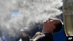 ຜູ້ຊົມກິລາເທັນນິສ Australian Open ຕາກອາຍນໍ້າ ທ່າມກາງອາກາດທີ່ຮ້ອນແຮງ, ນະຄອນ ແມລເບິນ, ອອສເຕຣເລຍ, 16 ມັງກອນ 2018.