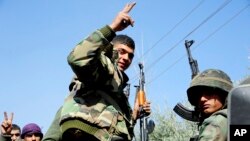 Foto yang dirilis Rabu 7 Maret 2018 oleh kantor berita resmi Suriah, SANA, menunjukkan para serdadu pemerintah Suriah, mengacungkan tanda kemenangan saat mereka maju selama pertempuran melawan para pemberontak Suriah di Ghouta bagian timur, Suriah (foto: SANA via AP)