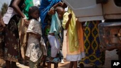 Muslim Children are lifted into a truck that had fallen into a ditch while turning around in Bangui, Central African Republic, Friday, Feb. 14, 2014. 