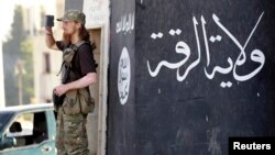 A militant Islamist fighter uses a mobile to film his fellow fighters taking part in a military parade along the streets of Syria's northern Raqqa province, June 30, 2014. 
