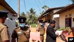 Hakim Sri Lanka Wasantha Ramanayake (kanan) dan polisi memeriksa suasana di luar sebuah rumah, tempat seorang gadis berusia sembilan tahun tewas di Delgoda, Sri Lanka, Minggu, 28 Februari 2021.