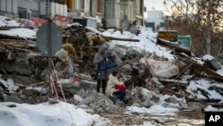 土耳其城市马拉蒂亚的地震灾民坐在房屋废墟上。 （2023年2月7日）