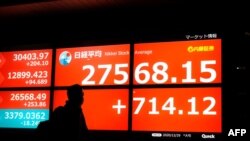 A pedestrian walks past an electronic quotation board displaying share prices of the Tokyo Stock Exchange in Tokyo on Dec. 29, 2020.