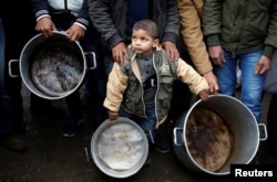 A Palestinian boy holds cooking pots during a protest against aid cuts, outside United Nations' offices in Gaza City January 24, 2018.