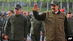 In this photo released by Miraflores Press Office, Venezuela's President Nicolas Maduro, right, accompanied by his Defense Minister Vladimir Padrino Lopez, waves upon his arrival to Fort Tiuna, in Caracas, Venezuela, May 2, 2019.