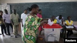 Une femme met son bulletin dans l'urne dans un bureau de vote de Cotonou, pour la présidentielle béninoise, le 6 mars 2016. (REUTERS/Akintunde Akinleye - RTS9I4A)