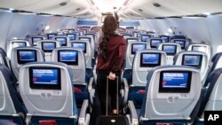 FILE - A passenger wears personal protective equipment on a Delta Airlines flight after landing at Minneapolis−Saint Paul International Airport, May 28, 2020.