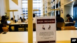 A sign about social distancing is placed on a table at the National Library in Singapore, March 16, 2020.