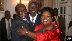 Zimbabwean President Robert Mugabe, left, celebrates with newly sworn-in vice presidents Joyce Mujuru, right, and Joseph Msika, center, State House, Harare, Oct. 2008 file photo.