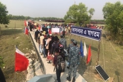 Rohingya refugees stand in line after they disembarked from a Bangladesh Navy ship to the island of Bashar Char in Noakhali on December 4, 2020.