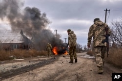 Ukrainian soldiers pass by a volunteer bus burning after a Russian drone hit it near Bakhmut, Donetsk region, on Nov. 23, 2023. (Shandyba Mykyta/Ukrainian 10th Mountain Assault Brigade via AP)