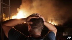 A man looks at a forest fire near the village of Larbaa Nath Irathen, near Tizi Ouzou, in the mountainous Kabyle region, 100 kilometers (60 miles) east of Algeria's capital of Algiers, Aug.11, 2021.