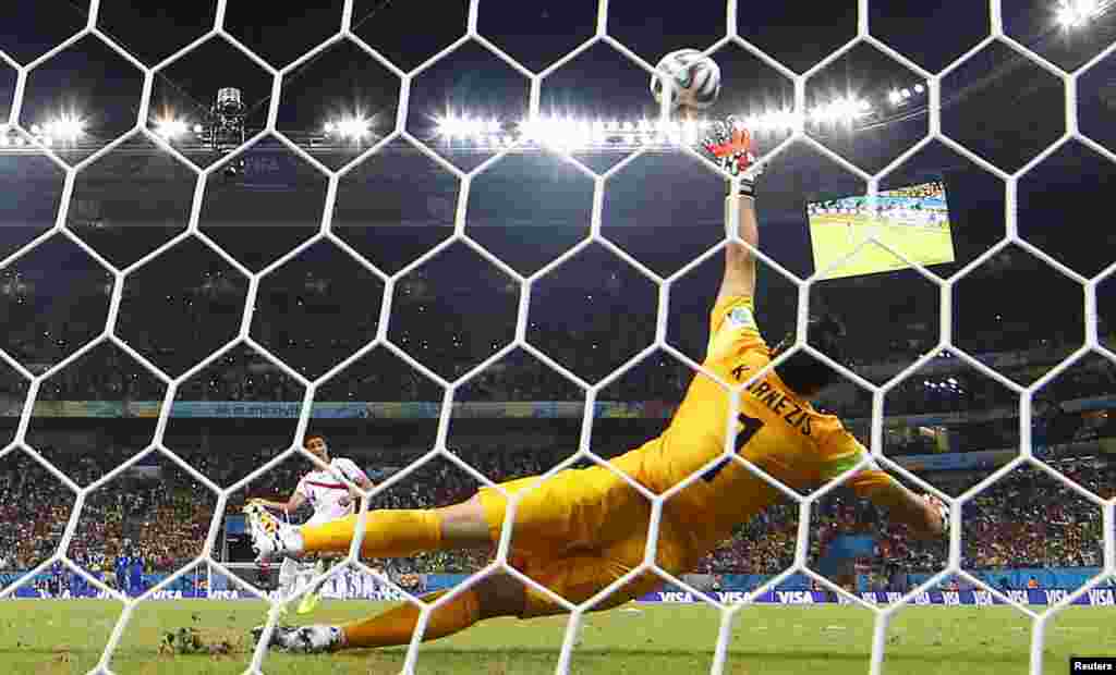 Costa Rica's Michael Umana scores past Greece's goalkeeper Orestis Karnezis during a penalty shootout at the Pernambuco arena in Recife, June 29, 2014.