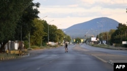 FILE - A pedestrian walks across an empty road, which usually experience heavy traffic in Gaborone on April 5, 2020 during the third day of the state of emergency in Botswana. 