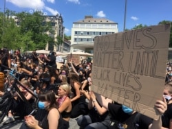 People sit and hold banners during a Black Lives Matter protest, following the death of George Floyd in Minneapolis police custody, in Zurich, Switzerland, June 13, 2020.
