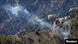FILE - A U.S. Army Apache helicopter flies over Afghanistan's Kunar province, June 4, 2012.