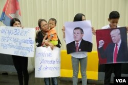 សន្តិសុខ​ដែល​ត្រូវ​បាន​ស្ថានទូត​សហរដ្ឋ​អាមេរិក​បញ្ឈប់​កាល​ពី​ប៉ុន្មាន​ខែ​មុន​និង​គ្រួសារ​របស់ពួកគេ​បាន​មក​ធ្វើ​បាតុកម្ម​តវ៉ា​រក​យុត្តិធម៌​ដោយ​អហិង្សា​នៅ​ខាង​មុខ​ស្ថានទូត​អាមេរិករាជធានី​ភ្នំពេញ​ ​កាល​ពីព្រឹក​ថ្ងៃទី​១៩ មិថុនា ឆ្នាំ ២០១៨។ (ទុំ ម្លិះ/VOA)