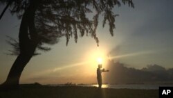 In this Wednesday, Jan. 6, 2016 file photo, a man is silhouetted against the rising sun in Singapore during his morning exercise along the eastern coast of Singapore. (AP Photo/Wong Maye-E, File)