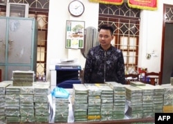 This handout taken by the Vietnam News Agency on February 25, 2018 and distributed on February 26 shows alleged drug smuggler and ringleader, Tran Van Bang, 31, standing before heroin bricks seized in the northern province of Cao Bang.
