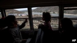 FILE - Central American children who are traveling with a caravan of migrants, look at the border wall from a bus carrying the group to a gathering of migrants living on both sides of the border, in Tijuana, Mexico, April 29, 2018. U.S. 