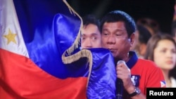 Philippine president Rodrigo 'Digong' Duterte holds a Philippine flag while addressing his supporters.