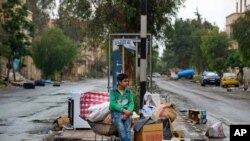 A Syrian boy waits his family to loads their belongings onto a bus in the town of Palmyra in the central Homs province, Syria, April 14, 2016.