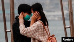 គូ​ស្រករ​មួយ​គូ​ពាក់​ម៉ាស់​នៅ​ពេល​ពួក​គេ​ឱប​ក្រសោប​គ្នា នៅ​ថ្ងៃ​នៃ​ក្ដី​ស្រឡាញ់ នៅ​ទីក្រុង​ហុង​កុង ប្រទេស​ចិន កាល​ពី​ថ្ងៃ​ទី​១៤ កុម្ភៈ ស្រប​ពេល​ដែល​ជំងឺ​កូរ៉ូណា កំពុង​រីក​រាល​ដាល់។