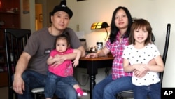 Adam Crapser (kiri) berfoto bersama anak perempuannya, Christal dan Christina, dan istrinya, Anh Nguyen, di ruang keluarga di Vancouver, Washington, 19 Maret 2015. (Foto: dok).