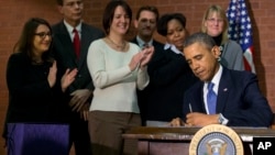 President Barack Obama signs the $1.1-trillion spending bill that funds the federal government through the end of September, at Jackson Place, a conference center near the White House in Washington, Jan. 17, 2014.