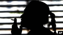 FILE - A woman smokes a cigarette in a parking lot in Bangkok, Thailand, May 27, 2010.