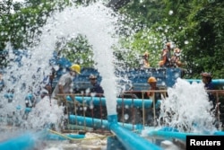 Rescue workers work next to water pumped out of Tham Luang cave complex, where members of a youth soccer team and their coach have been found alive, in the northern province of Chiang Rai, Thailand, July 5, 2018.