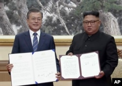 In this image made from video provided by Korea Broadcasting System (KBS), S. Korean President Moon Jae-in, left, and N. Korean leader Kim Jong Un pose after signing documents in Pyongyang, North Korea Wednesday, Sept. 19, 2018.