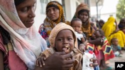 FILE - A woman feeds her child at a clinic in a rural village in Afar, Ethiopia, Jan. 26, 2016.
